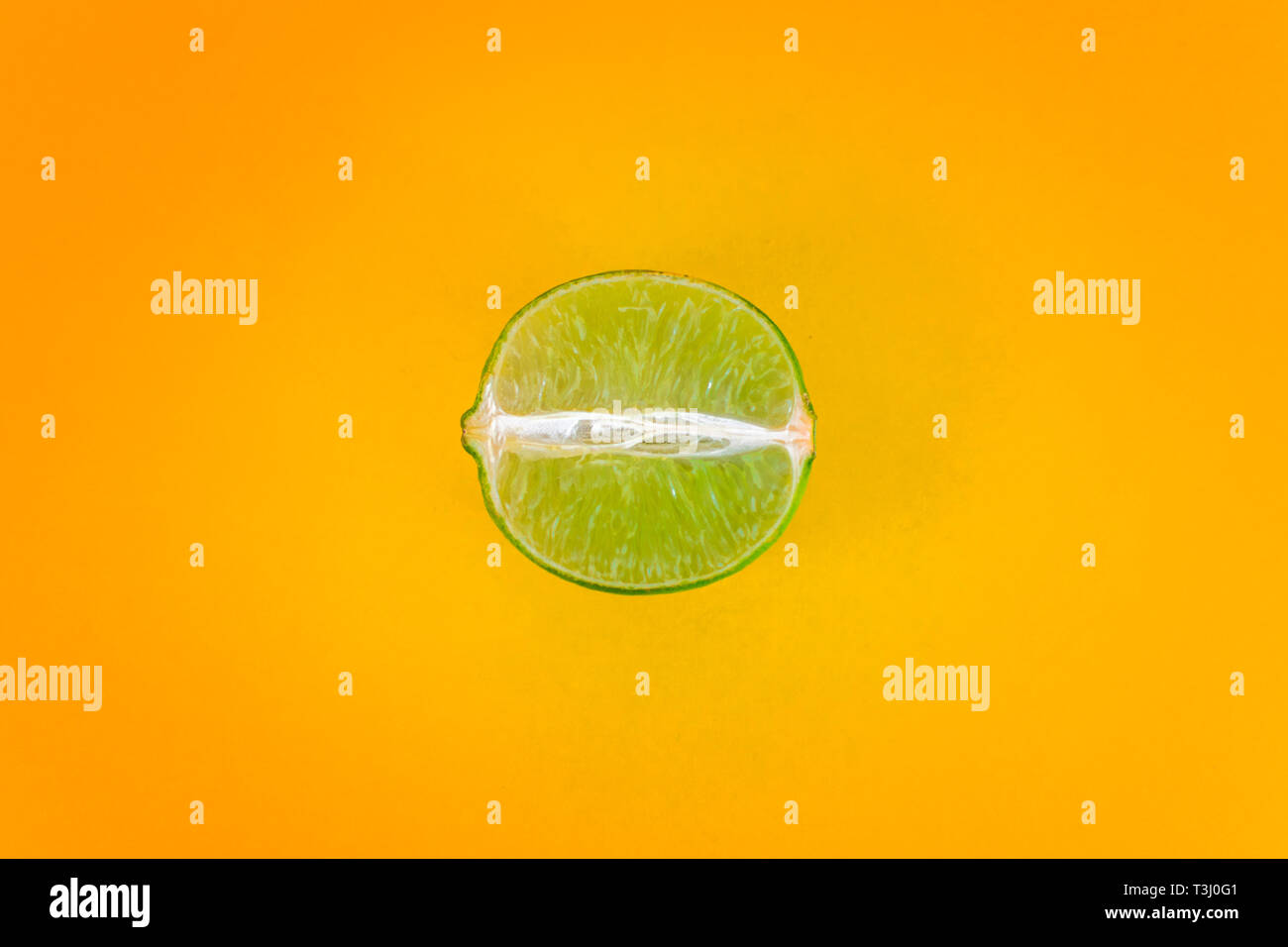 La Pop art style verde fetta di limone sulla vibrante giallo il colore dello sfondo. Minimo lay piatto food texture con abbondanza di spazio libero per gli inserti in tutto il Foto Stock