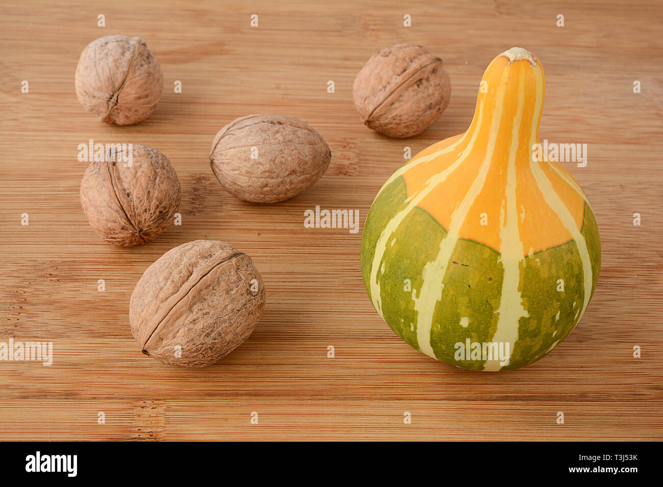Noci e zucca decorativa su sfondo di legno, vista ravvicinata con copia spazio, decorazione di autunno Foto Stock