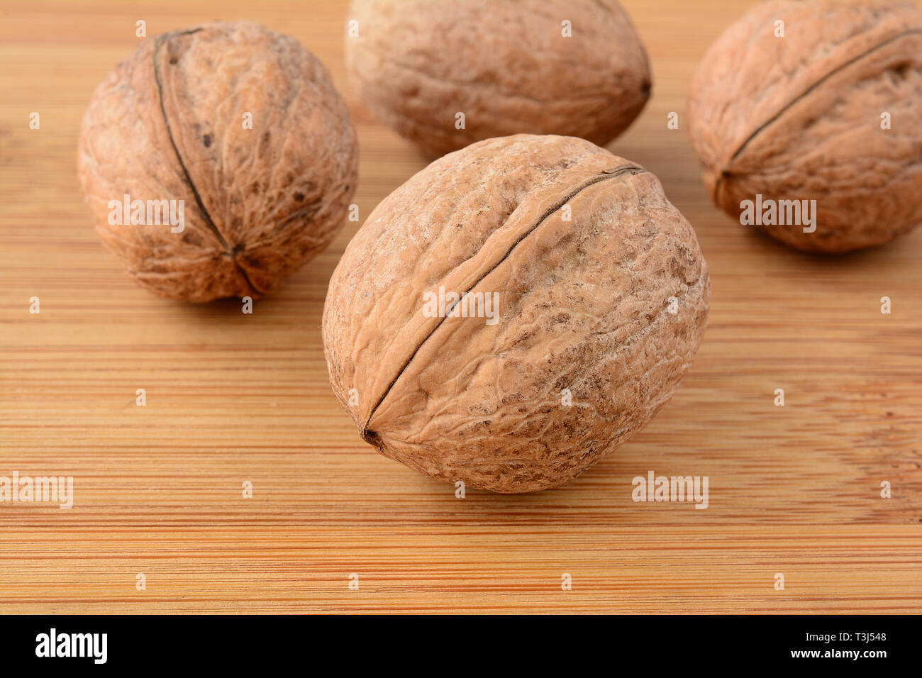 Wallnuts su legno, uno in primo piano e tre in background, sullo sfondo di legno, vista ravvicinata, la profondità di campo Foto Stock