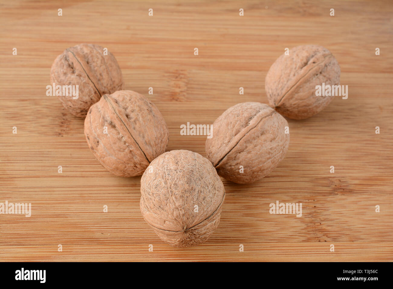 Noci su sfondo di legno allineate nella lettera V forma, vista ravvicinata Foto Stock