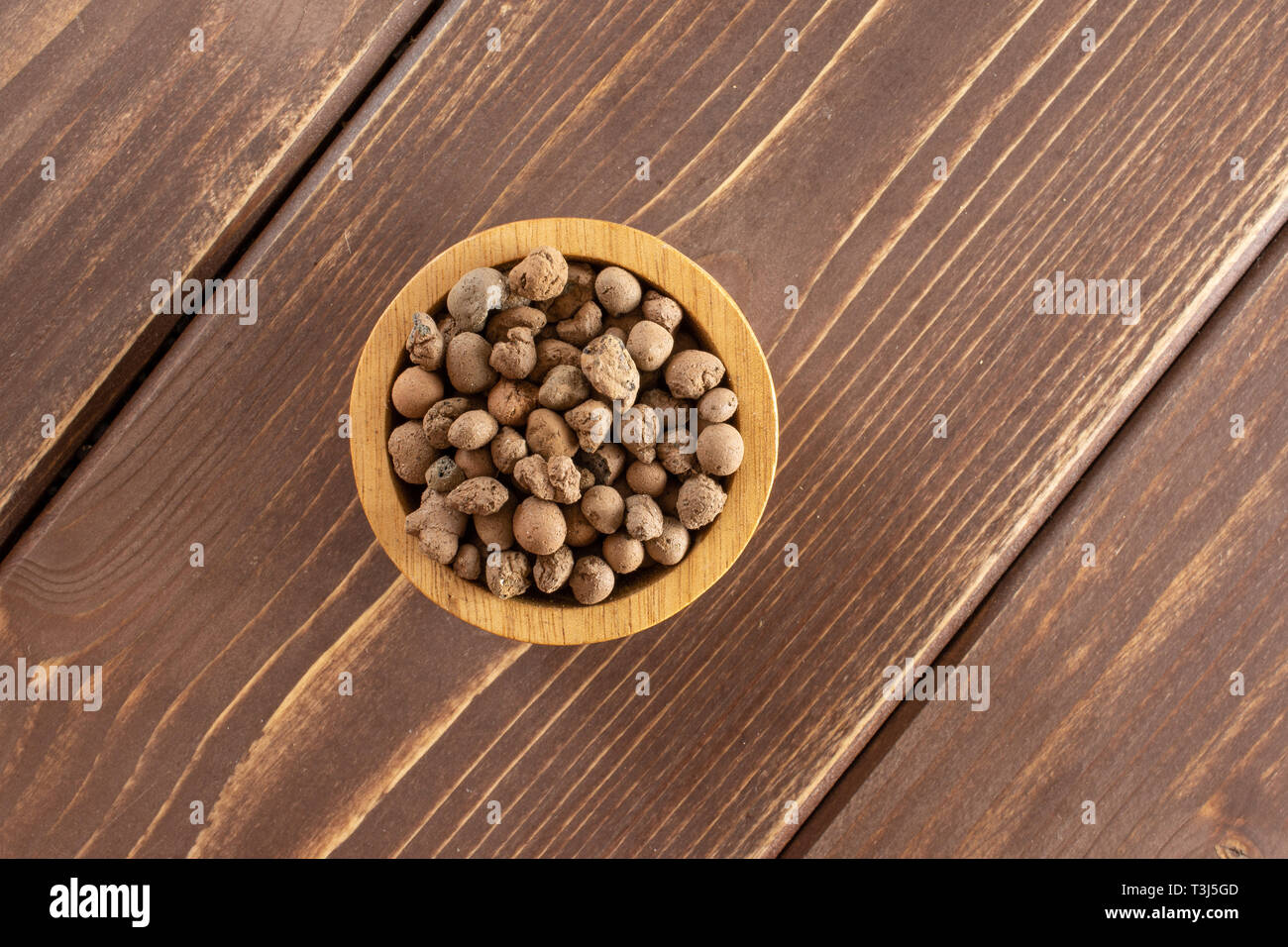 Lotto intero di argilla marrone ciottoli (leca) con ciotola di legno flatlay su legno marrone Foto Stock