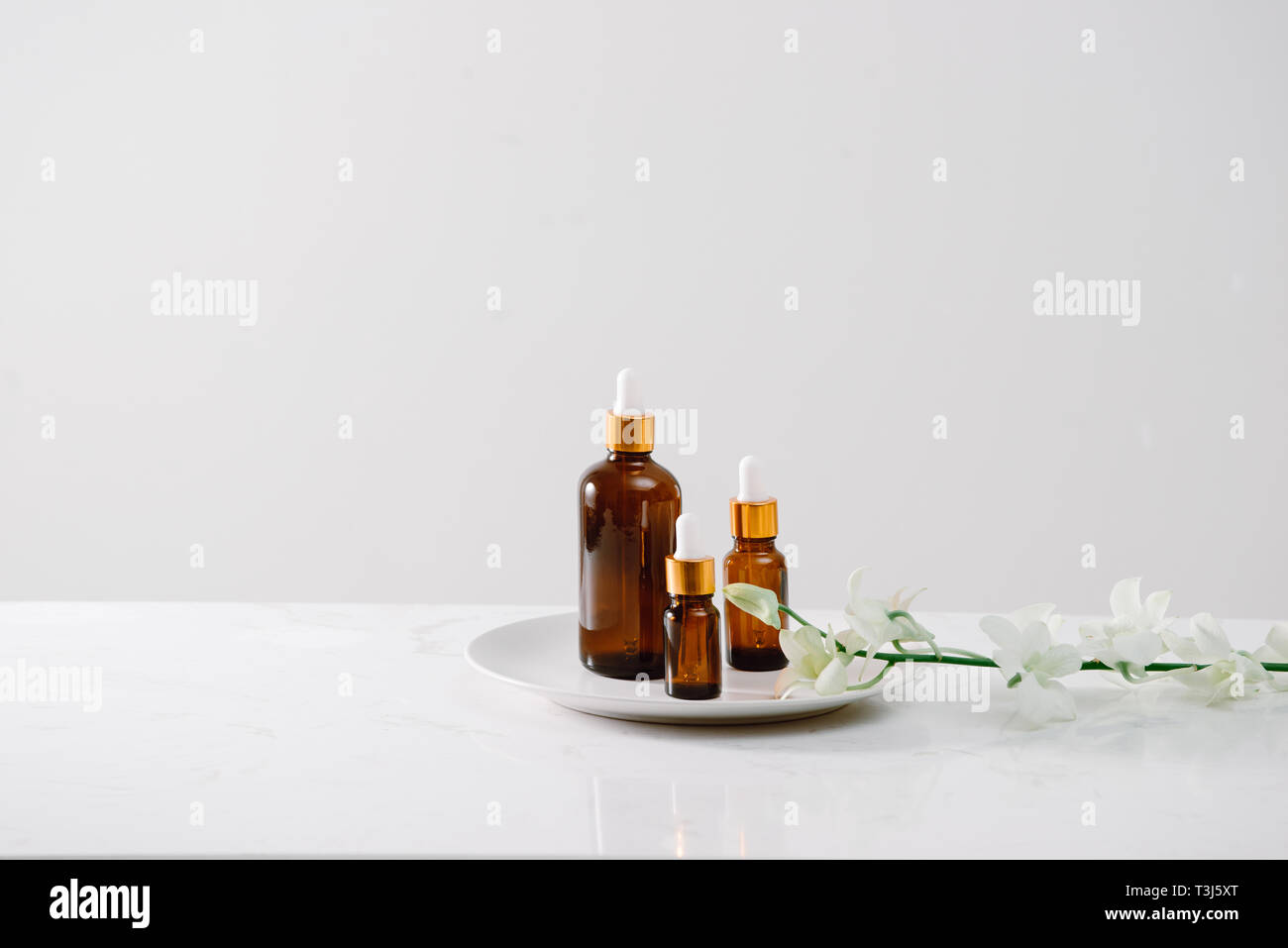 Impostazione di Spa con orchidee e olio essenziale in una bottiglia di vetro, aromaterapia concept Foto Stock