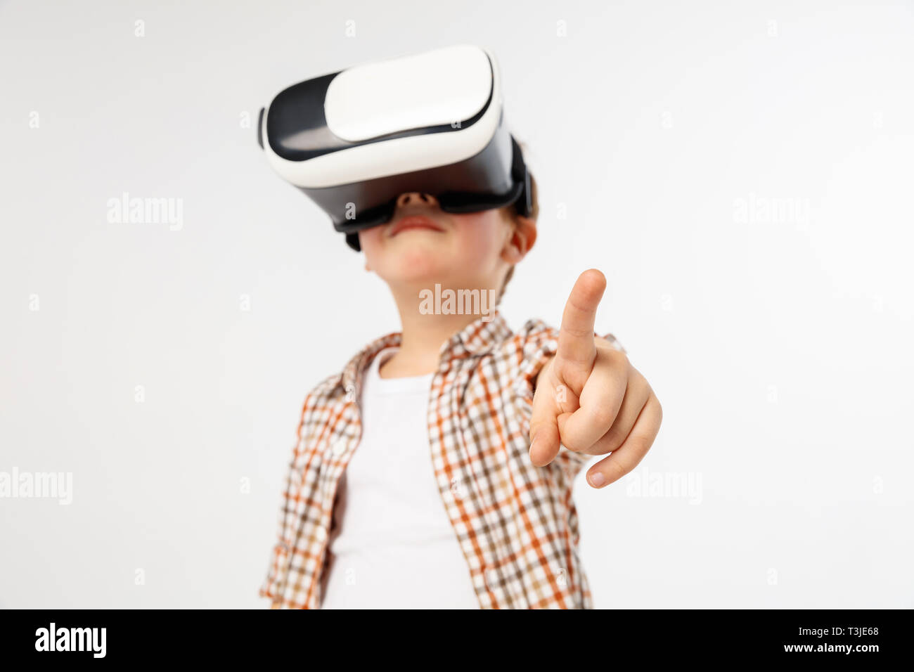 Scegli la tua strada. Little Boy o bambino rivolto verso lo spazio vuoto con occhiali per realtà virtuale isolato su bianco di sfondo per studio. Concetto di tecnologia all'avanguardia, video giochi, l'innovazione. Foto Stock