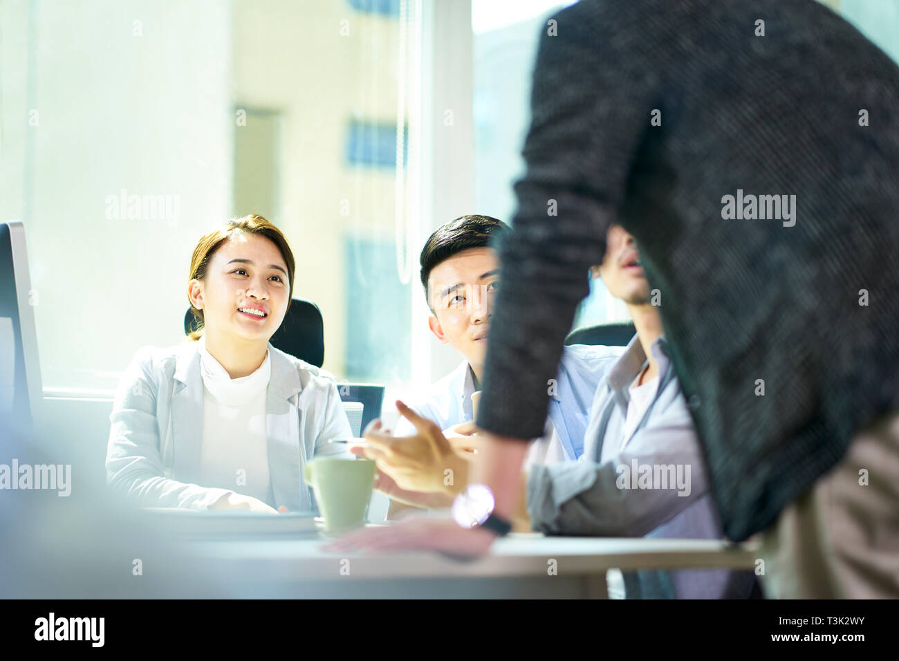 Quattro giovani imprenditori asiatici riuniti a discutere di office business plan utilizzando tablet PC. Foto Stock