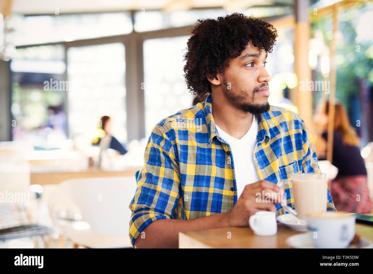 Avvio di un nuovo giorno al cafe'. Vista laterale del giovane africano holding tazza di caffè un Foto Stock