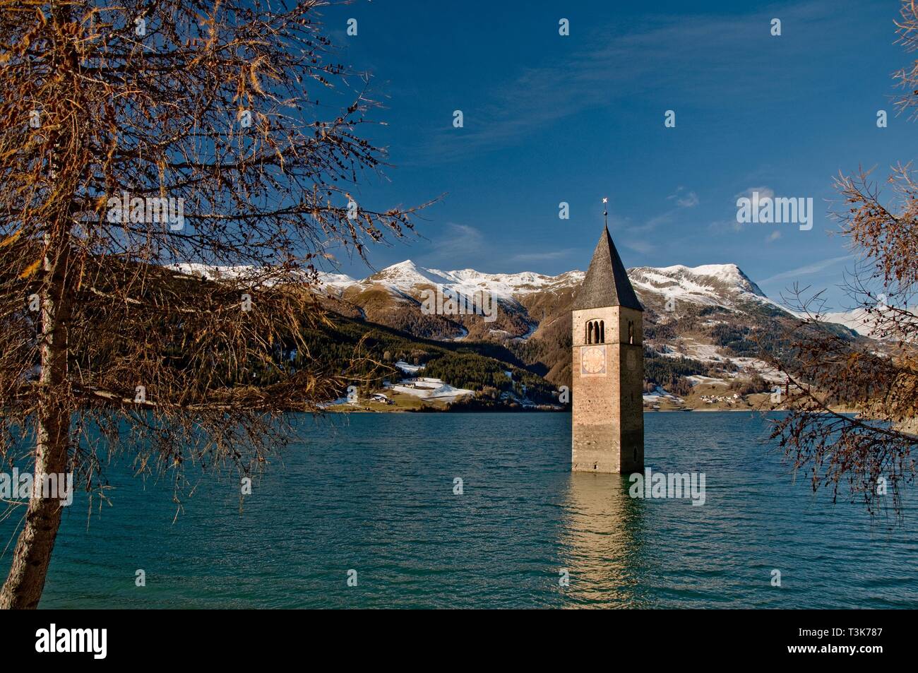 Il campanile della chiesa della ex chiesa parrocchiale Sankt Katahrina di Graun in Reschensee, sullo sfondo il Piz Lad, Val Venosta, Alto Adige, Italia Foto Stock