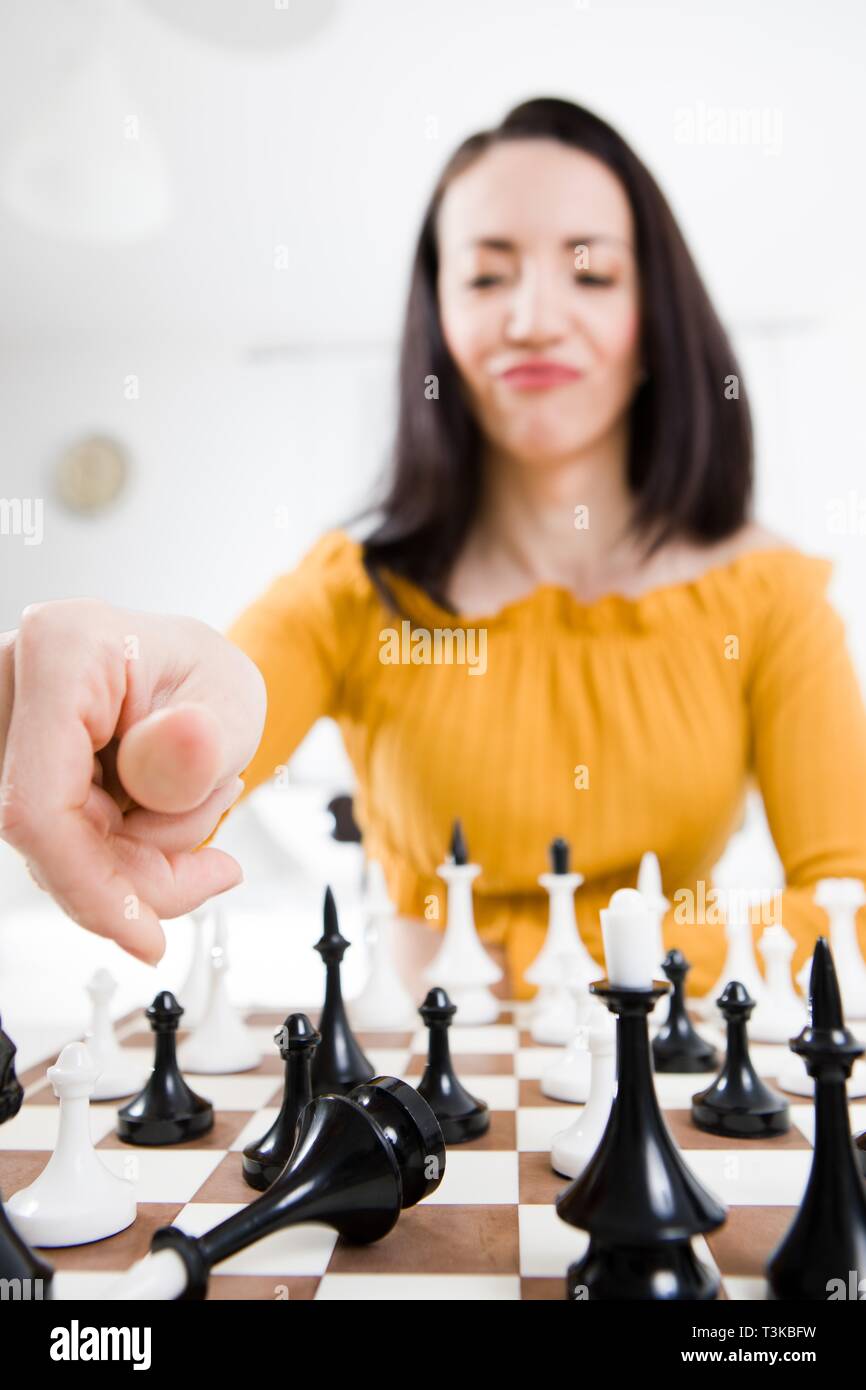 Donna in abito giallo seduti di fronte a scacchi e dando Check Mate Foto Stock