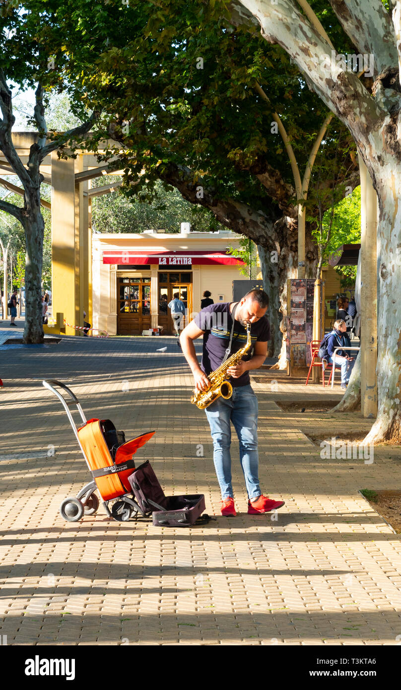 Busker suona la sassofa dell'alto e picchiando il piede in Alameda de Hercules a Siviglia Foto Stock