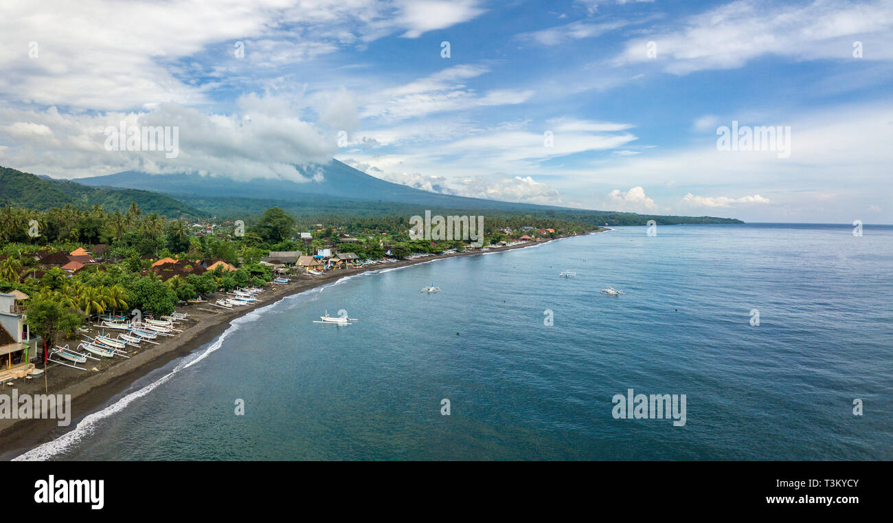 Panoramica vista aerea della Spiaggia di Amed in Bali, Indonesia. Tradizionali barche da pesca chiamato jukung sulla spiaggia di sabbia nera e Gunung Agung vulcano nel Foto Stock