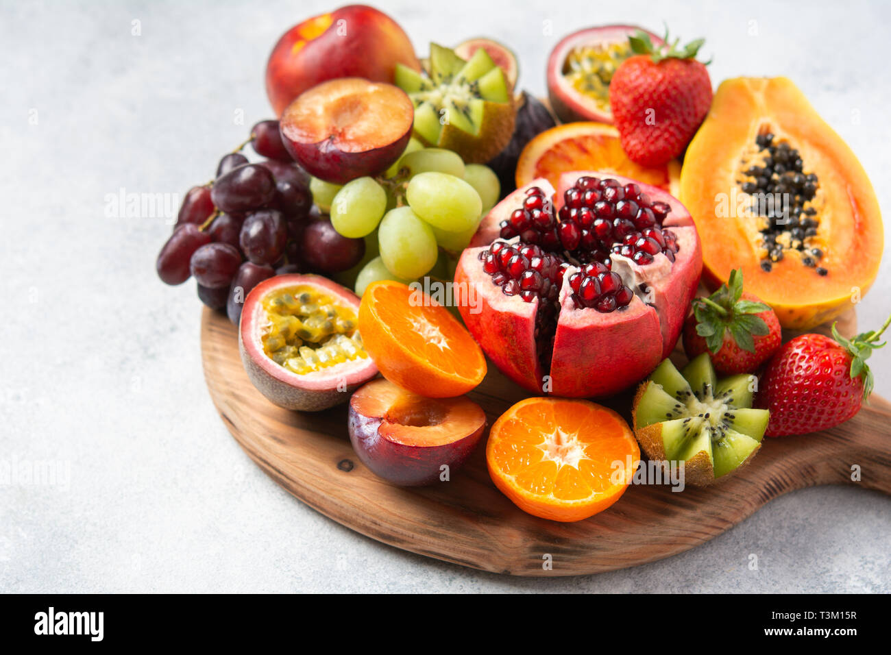 Deliziosa frutta melograno arance Papaia Frutti della passione sulla tavola di legno su bianco e messa a fuoco selettiva Foto Stock