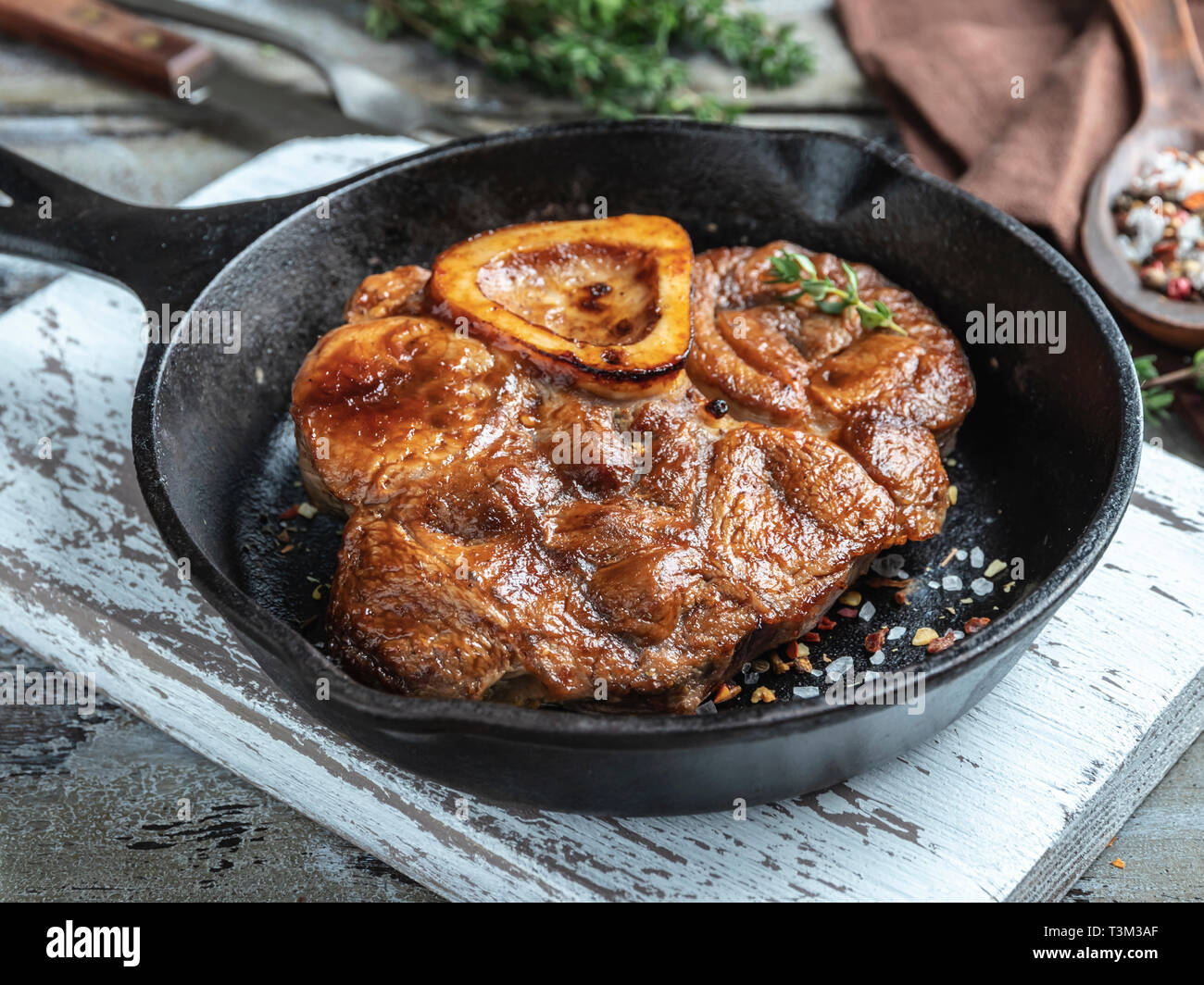 Osso Buco cucinato Stinco di vitello su una porzione padella di ferro,  salsa rossa, spezie Foto stock - Alamy