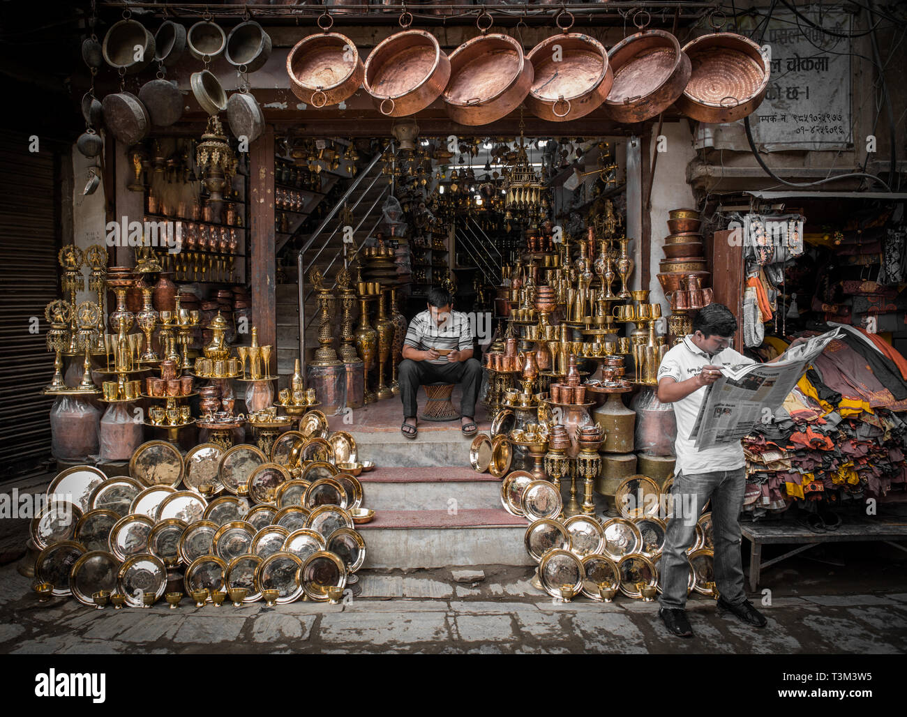 Gli uomini alla ricerca dopo un negozio a motivo chowk, vendita di rame battuto e ottone fuso, Kathmandu, Nepal Foto Stock