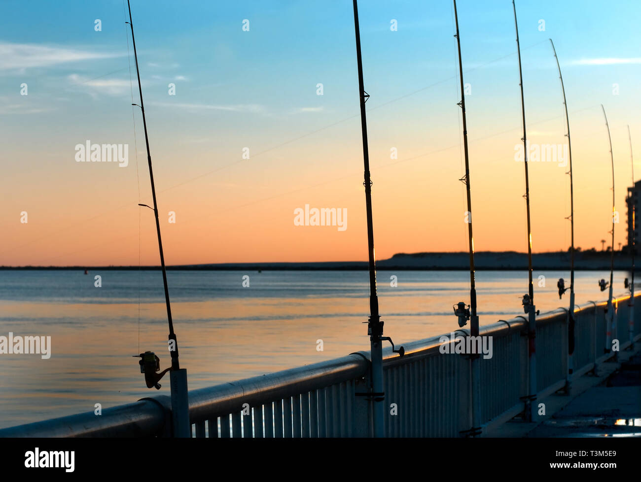 Poli di pesca rimangono inattivi come il sole tramonta a Florida punto pier, nov. 12, 2009, in Orange Beach, Alabama. Foto Stock