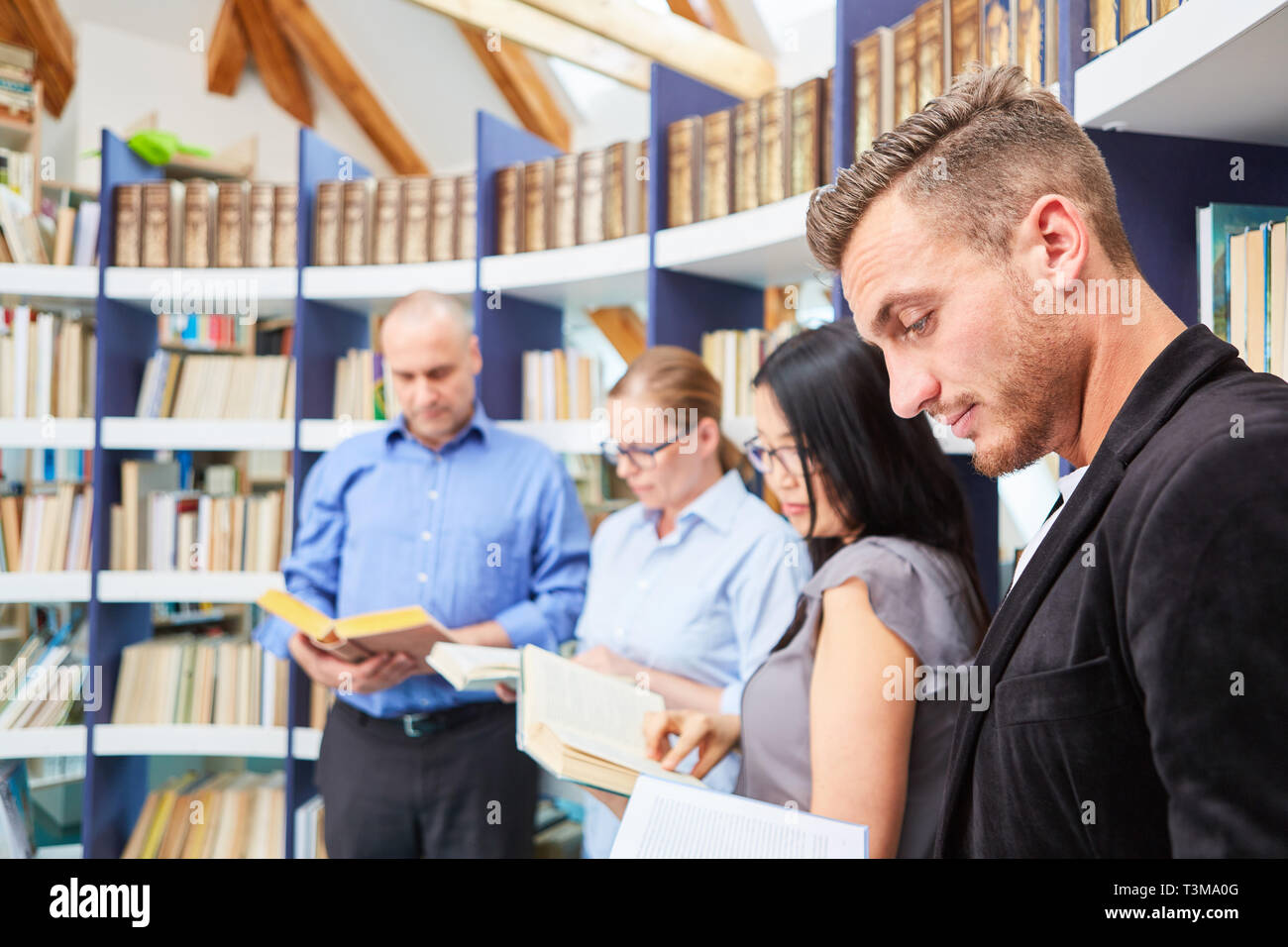 Gruppo di persone durante la lettura del libro insieme nella biblioteca della community college Foto Stock