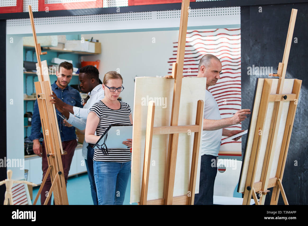 La gente in una classe di pittura per principianti presso il cavalletto in studio della community college Foto Stock