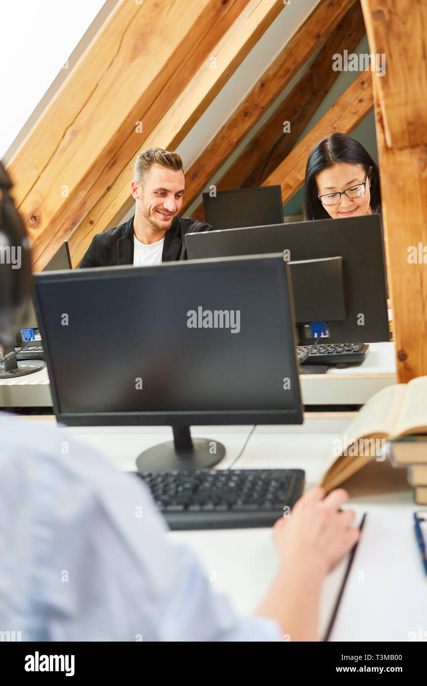 Colleghi di lavoro in ufficio coworking in corrispondenza di varie stazioni di computer in rete Foto Stock
