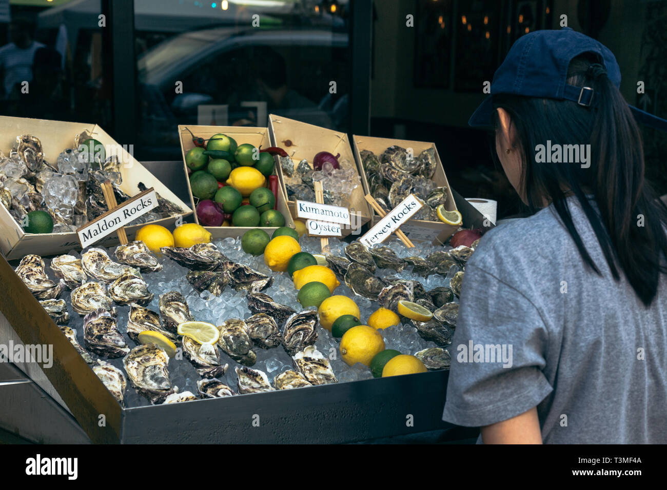 Donna scelta di ostriche presso il Mercato di Portobello a Londra, Regno Unito Foto Stock