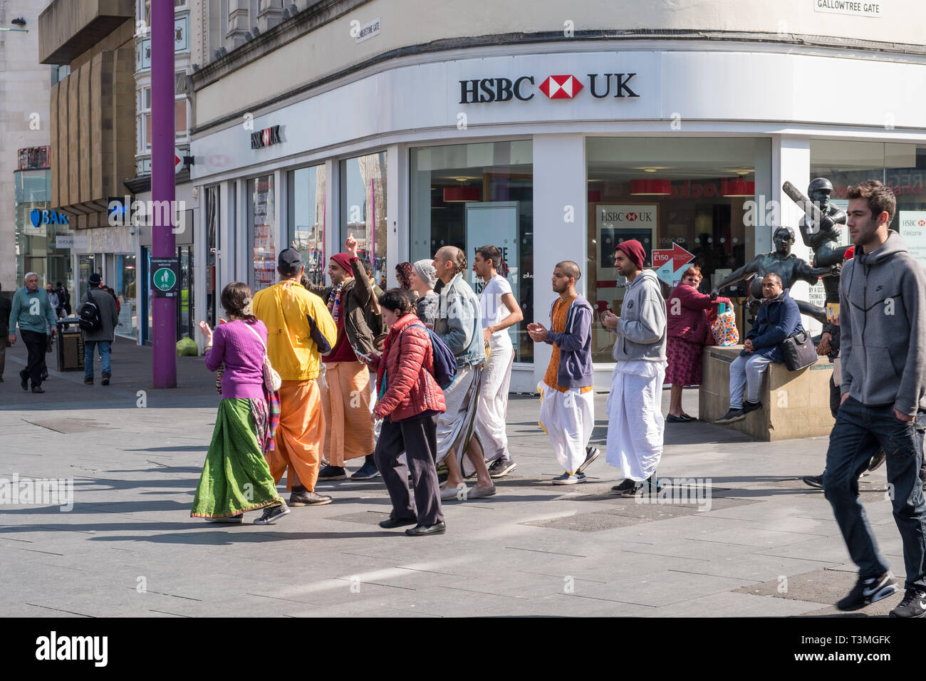 Un gruppo di Hare Krishna seguaci in abiti colorati chant come essi a piedi attraverso il centro di Leicester, Regno Unito Foto Stock