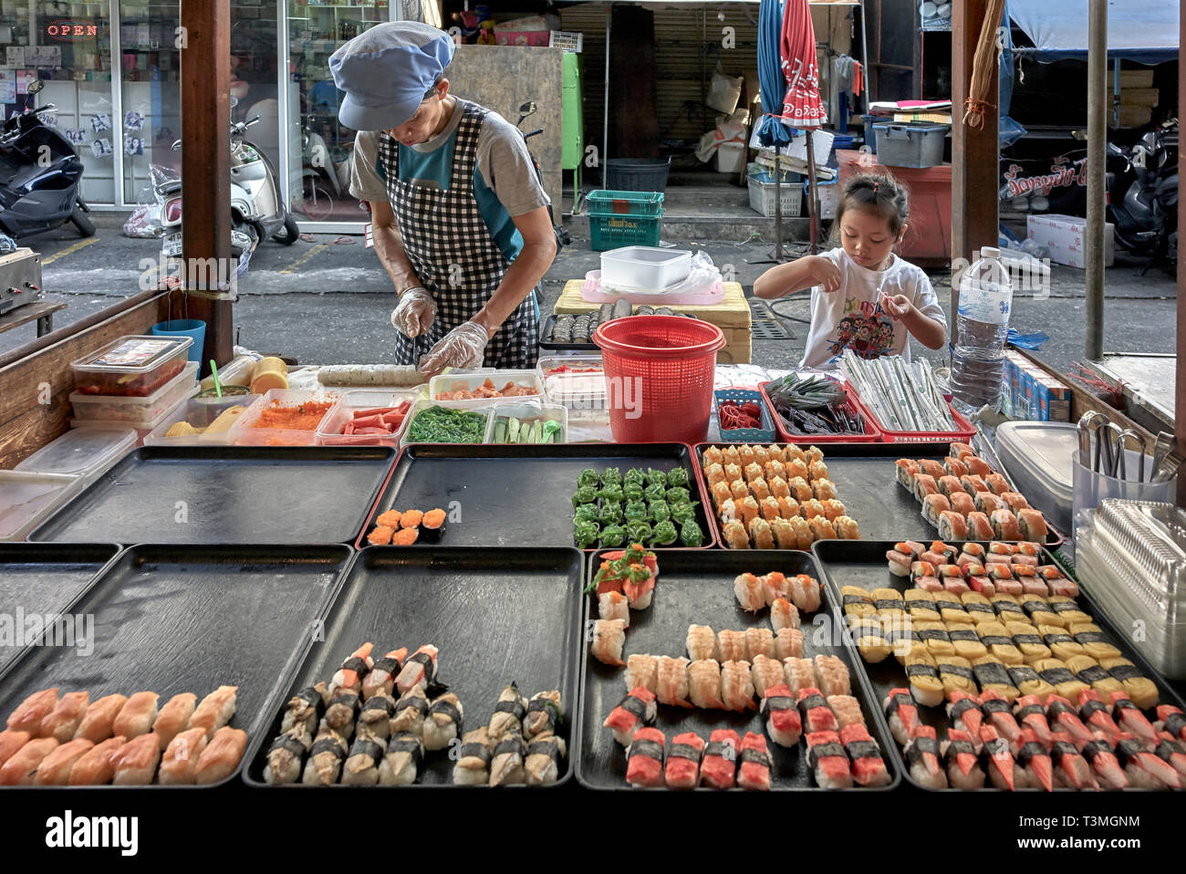 Thailandia street food bancarella vendendo il sushi e con bambino aiutando la madre Foto Stock