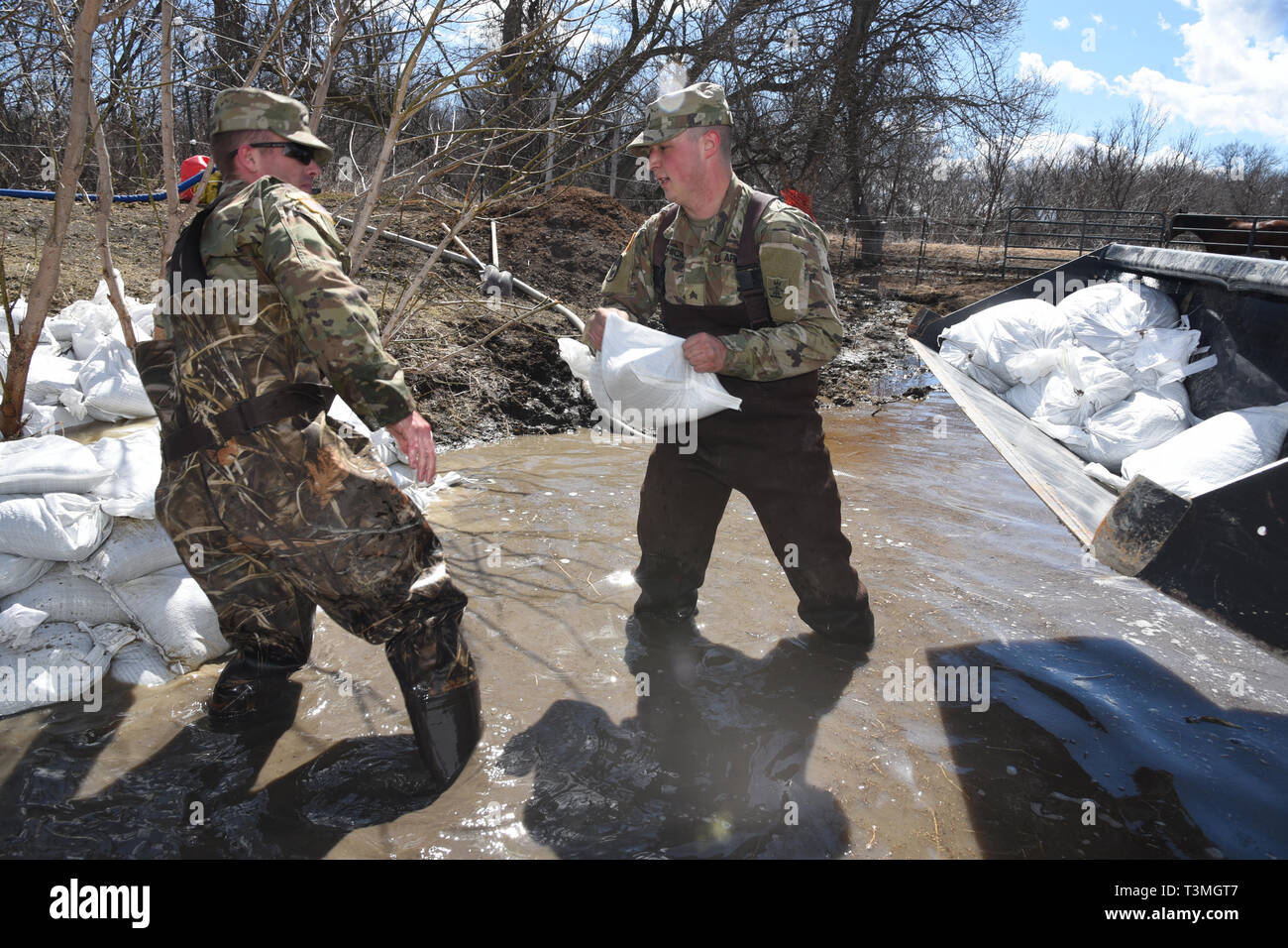 Il Dakota del Nord Esercito Nazionale guardie riposare in acqua di inondazione in quanto luogo di sacchi di sabbia per blocco rising inondazione dal backup attraverso un canale sotterraneo di drenaggio in una fattoria rurale della contea di Cass 8 Aprile 2019 vicino al West Grand Forks, North Dakota. Il record di allagamento dovrebbe peggiorare a fine inverno tempesta di barili nel midwestern Stati Uniti nei prossimi giorni. Foto Stock