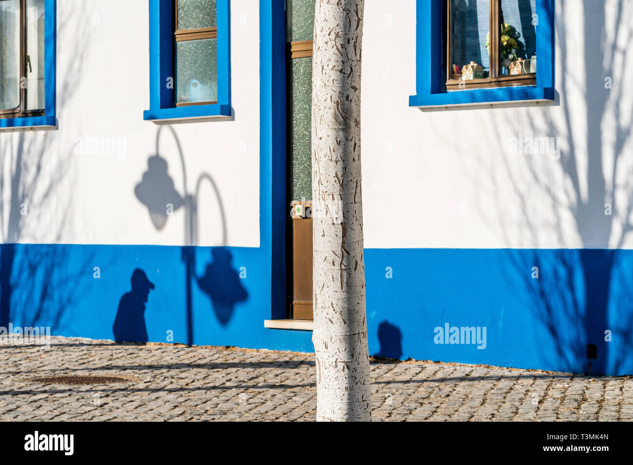 Ombre scure di persone, albero e lanterna sulla tradizionale casa di pescatori a Tavira, Algarve, PORTOGALLO Foto Stock