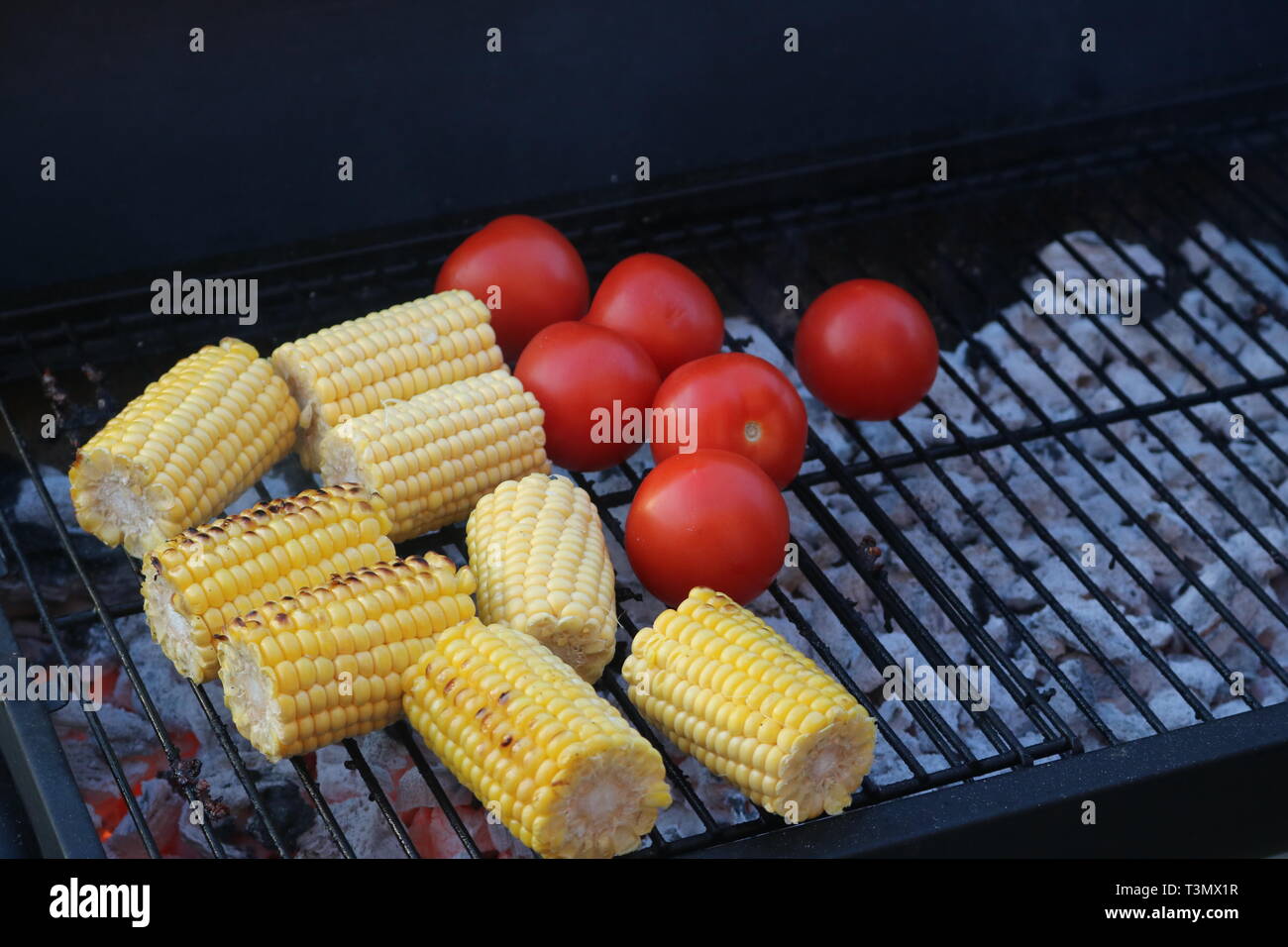 Sulla pannocchia di mais e pomodori su un barbecue Foto Stock