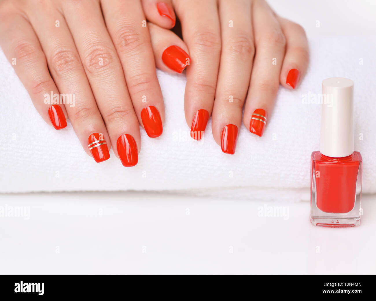 Manicure - bella donna curati le unghie con rosso smalto per unghie su Morbido asciugamano bianco. Foto Stock
