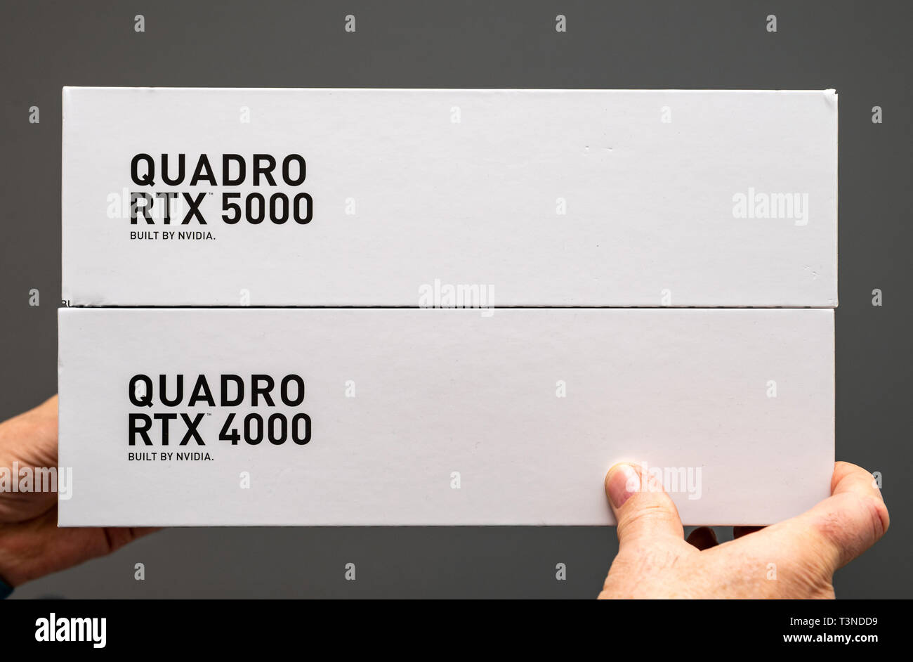 Parigi Francia - Mar 28 2019: Senior uomo che mostra due scatole di cartone prima di unboxing di Nvidia Quadro 4000 RTX e 5000 GPU per workstation dotate di nuovi multiprocessori streaming anime tensore - Sfondo grigio Foto Stock