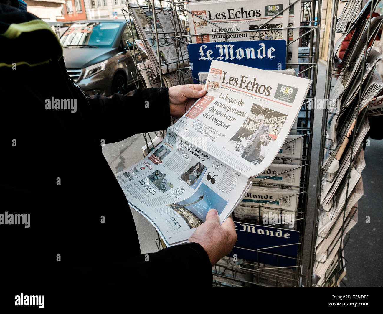 Parigi, Francia - 29 Mar 2019: Edicola chiosco premere senior mano maschio acquisto economico più recente Les Echo con notizie su Peugeot auto maker sul coperchio anteriore Foto Stock