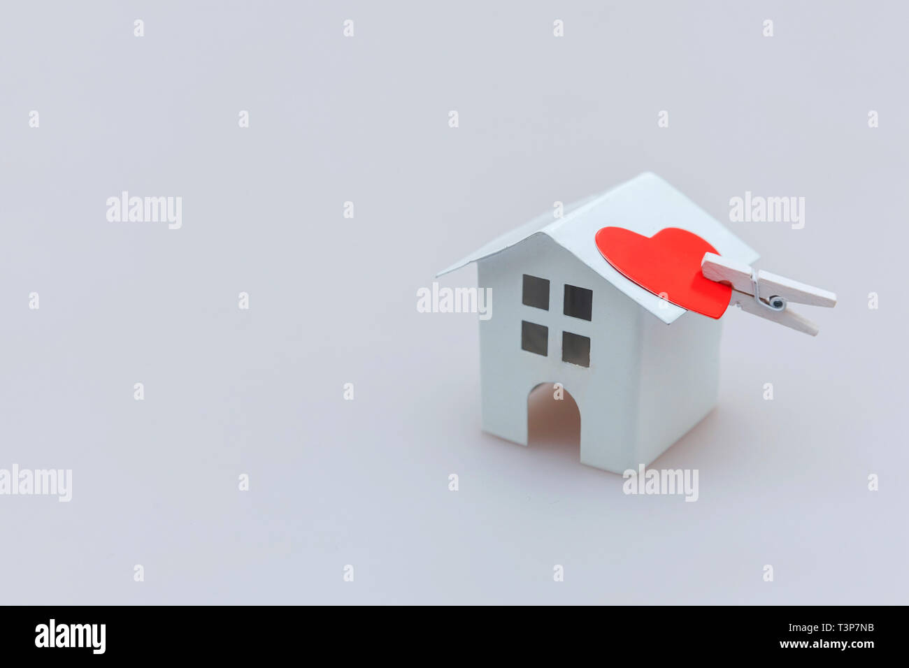 Semplicemente dal design minimale con bianco in miniatura toy house e cuore rosso isolato su sfondo bianco. Ipoteca di proprietà di assicurazione casa da sogno concetto. Copia Foto Stock