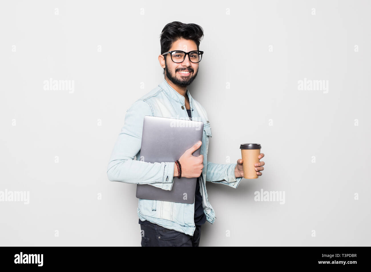 Giovani indiani Uomo con laptop e prendere via caffè permanente bianco isolato su sfondo bianco Foto Stock