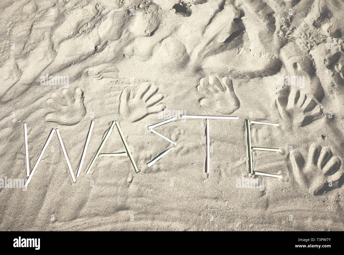 Parola di rifiuti di plastica cannucce sulla sabbia, retrò dai toni di colore dell'immagine. Foto Stock