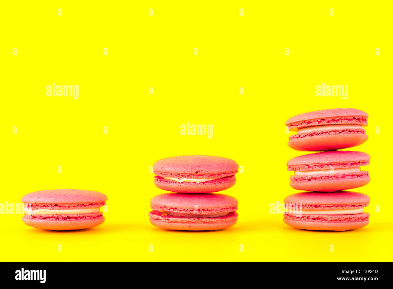 Amaretti rosa su sfondo giallo. Concetti di classificazione e la crescita Foto Stock