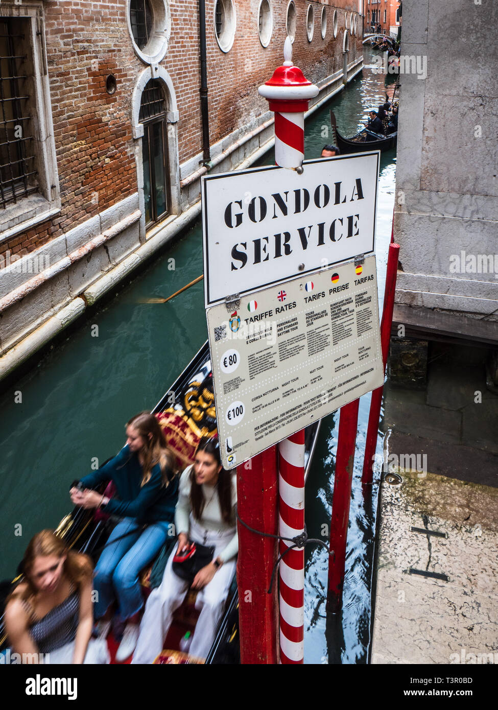 Venezia turisti - i turisti a bordo di una gondola a Venezia passano una gondola imbarcadero. Foto Stock