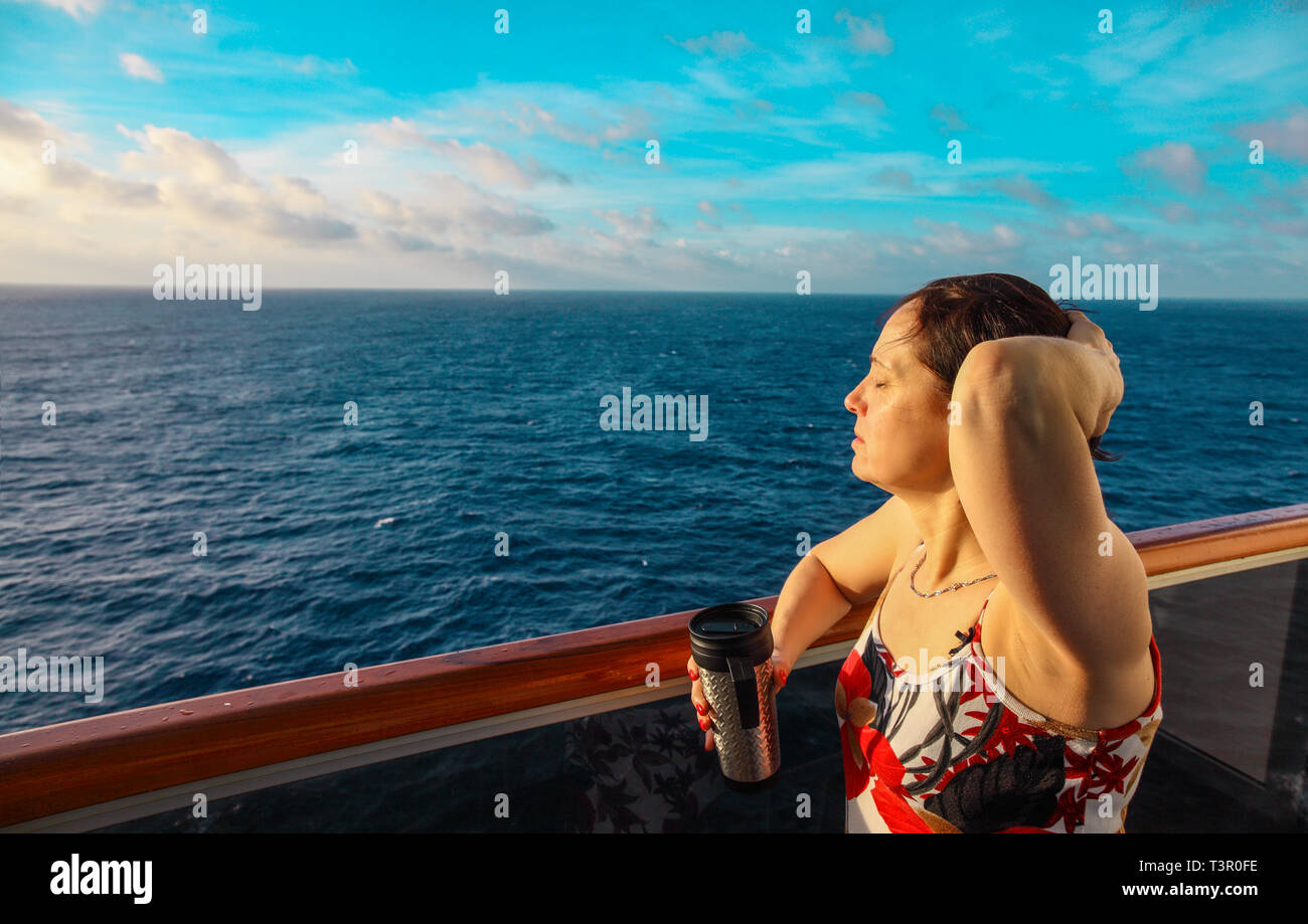 Donna sul balcone di una nave da crociera al tramonto Foto Stock