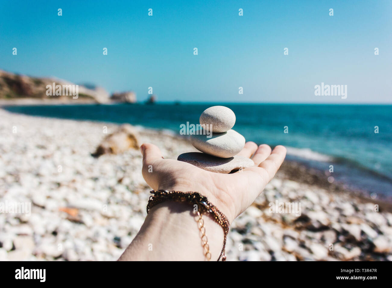 Equilibrio di pietre sulla mano contro lo sfondo del mare. Il concetto di pace della mente, armonia, spiritualità Foto Stock