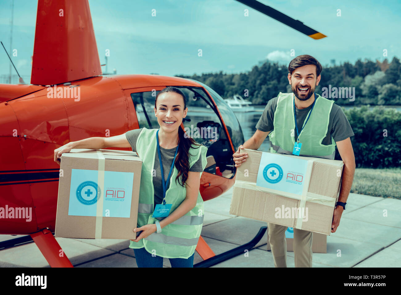 Happy good-looking duro lavoro di volontari che trasportano le scatole pesanti con aiuti Foto Stock