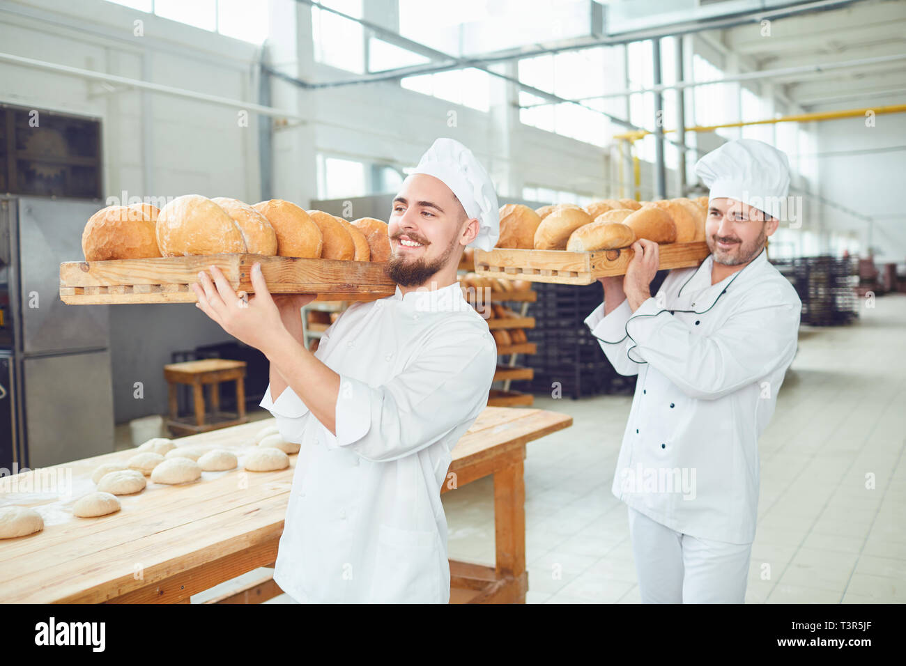 Due fornai uomini portano vassoi con il pane al forno. Foto Stock