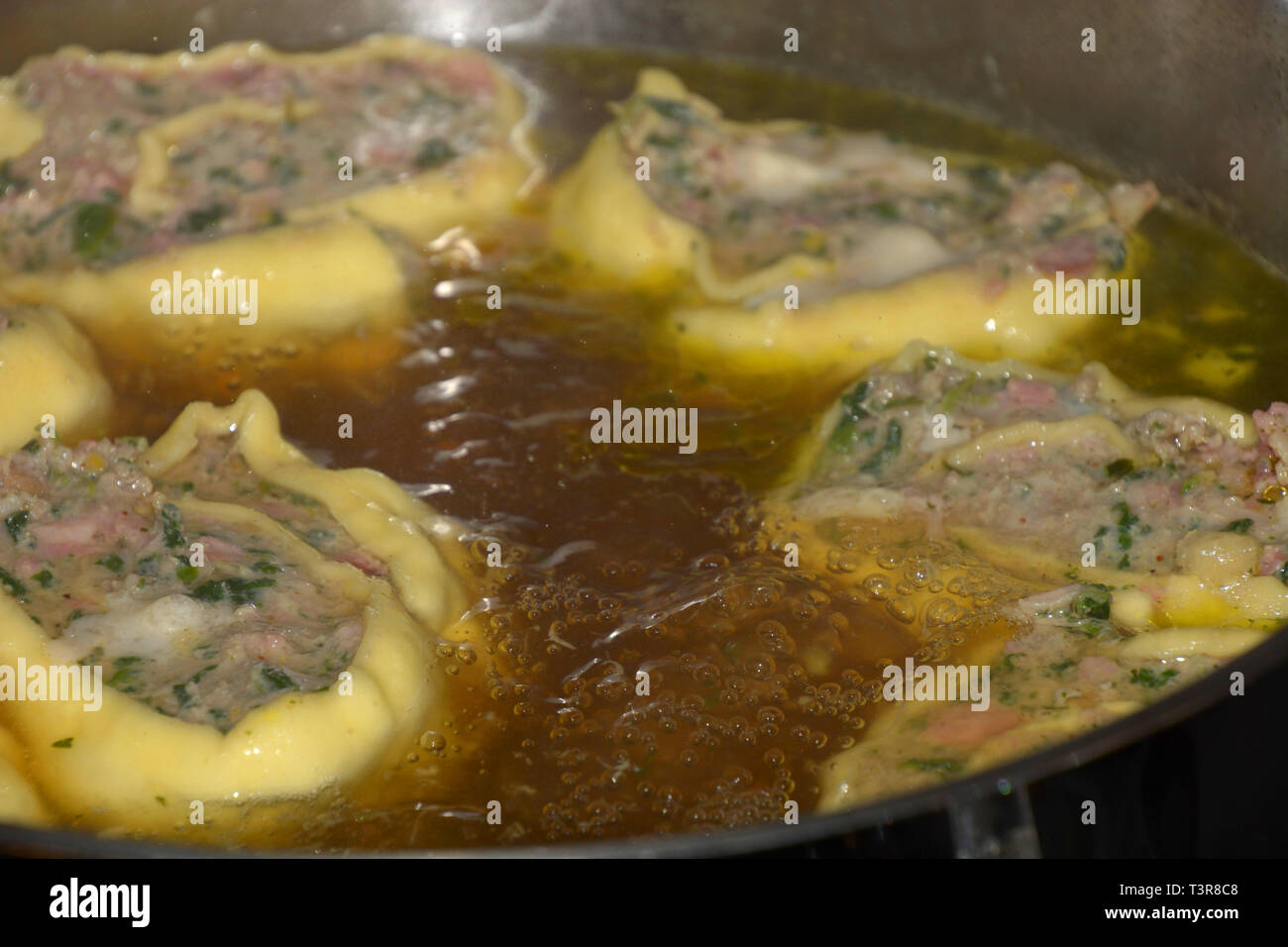 Deliciois maultaschen sveva ripiena di spinaci e carne, laminati in casa sveva ravioli di carne galleggianti in brodo caldo in una pentola di metallo Foto Stock