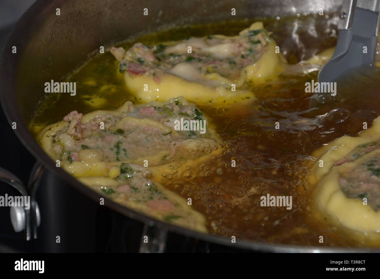 Laminati in casa sveva ravioli di carne galleggianti in brodo caldo in una pentola di metallo, svevo maultaschen ripiena di spinaci e carne Foto Stock