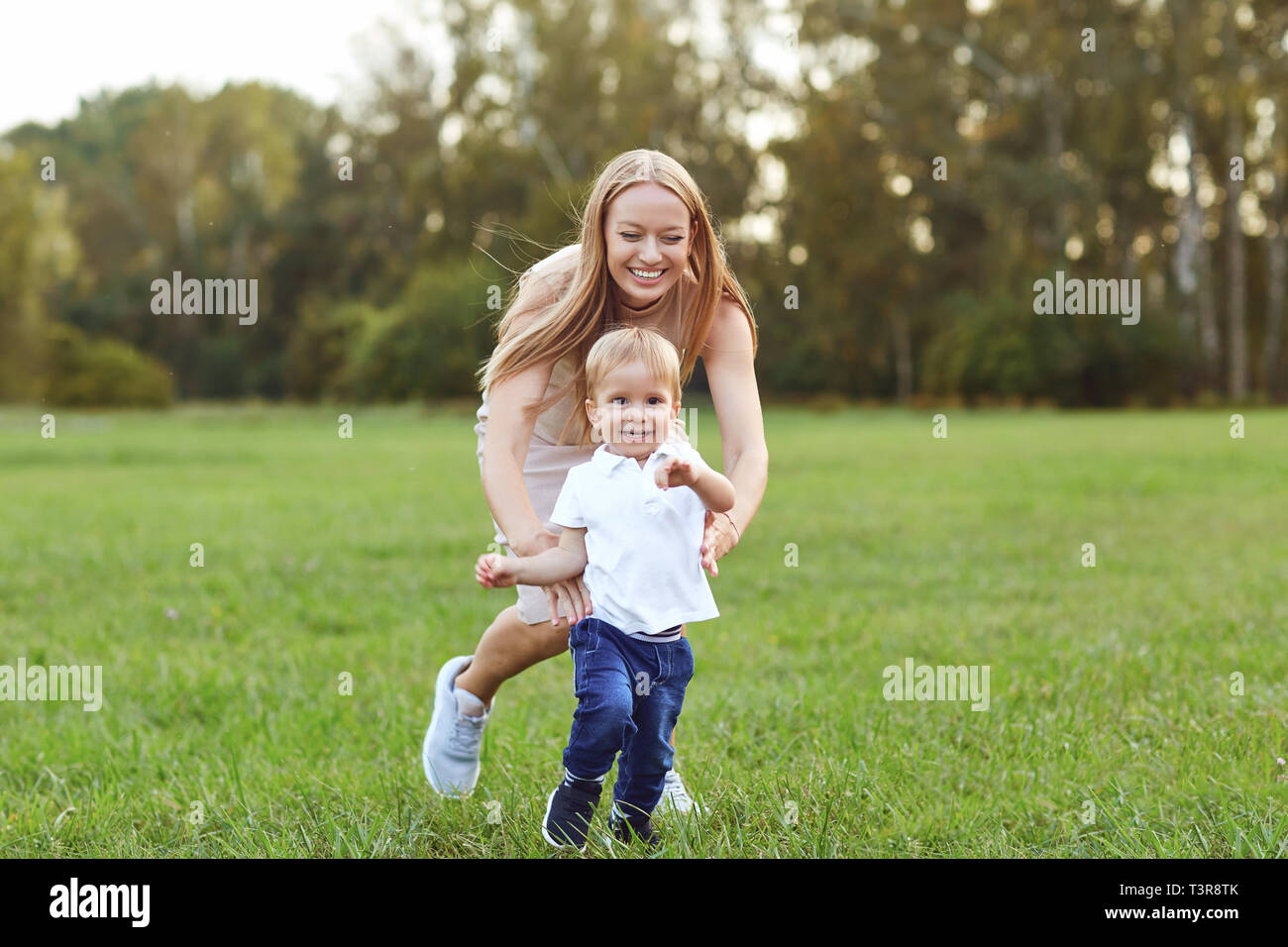 Ridendo donna con little boy sul prato verde Foto Stock