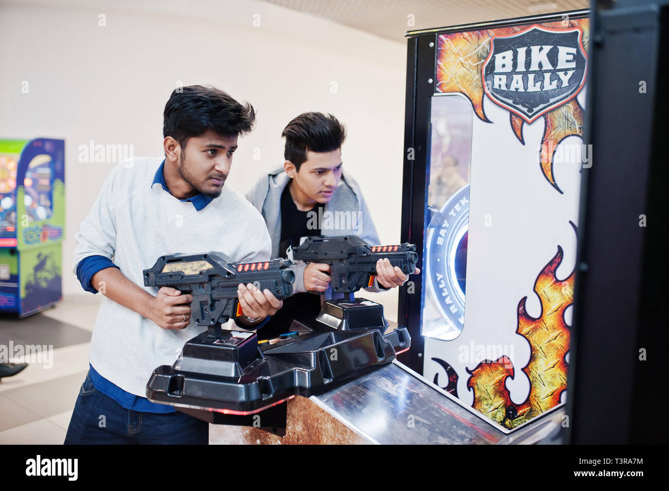 Due ragazzi asiatici competere sul simulatore sparatutto arcade gioco macchina. Foto Stock