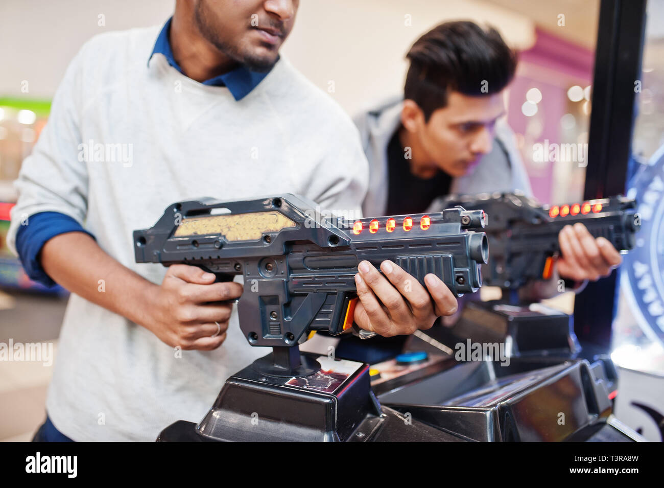 Due ragazzi asiatici competere sul simulatore sparatutto arcade gioco macchina. Foto Stock