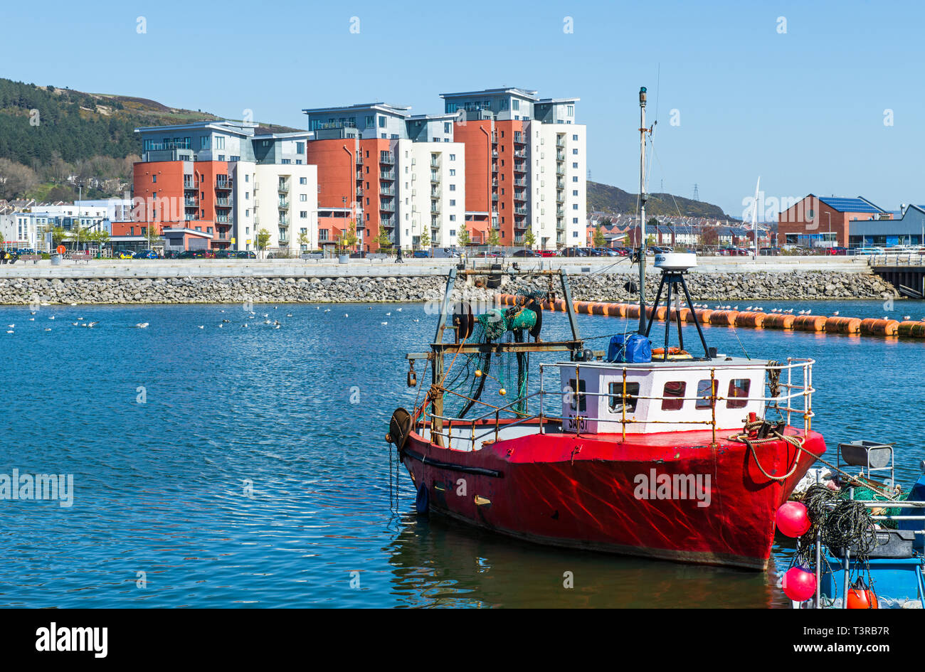 Guardando al di là del fiume Tawe a Swansea a Swansea SA1 e l'Universtiy del Galles e la costruzione di un locale rosso barca da pesca, Galles del Sud Foto Stock