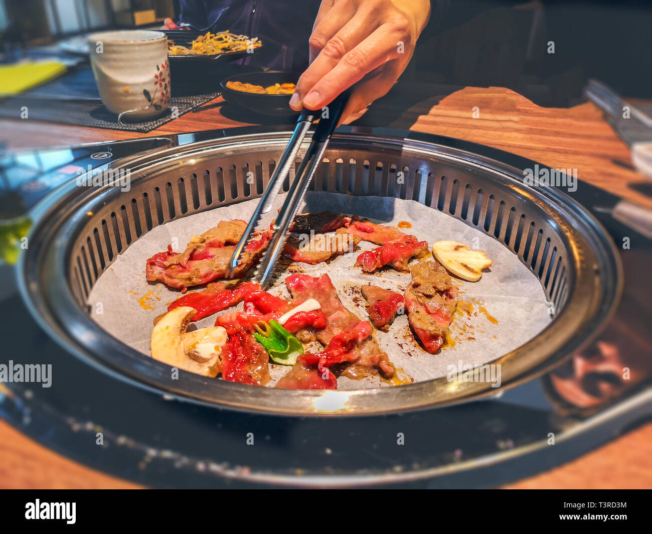 Femmina lato cottura bulgogi coreano griller carni bovine in una griglia per il barbecue sul ristorante tabella Foto Stock