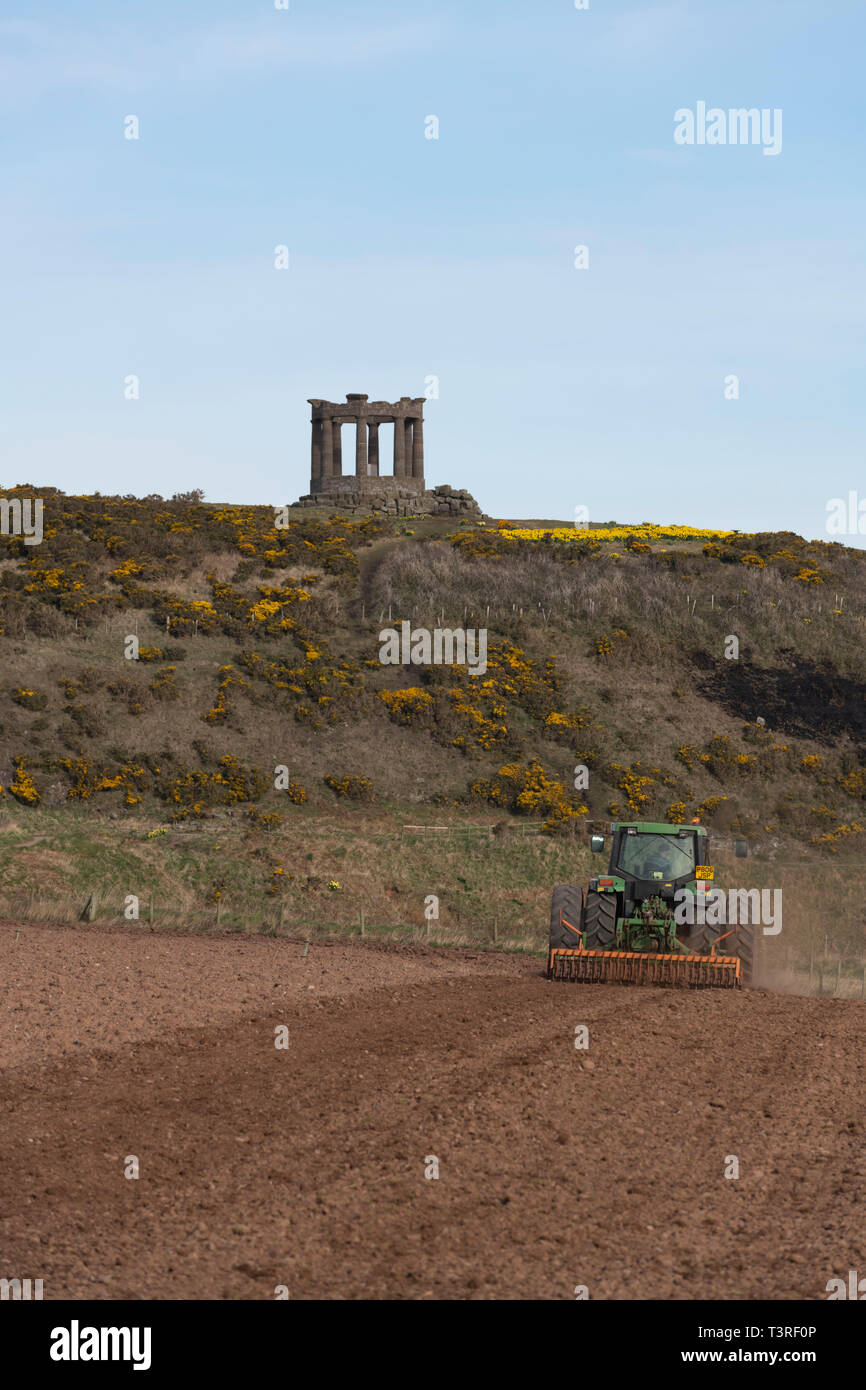 Un agricoltore erpici un campo al di sotto del Memoriale di guerra nei pressi di Stonehaven in Aberdeenshire Foto Stock