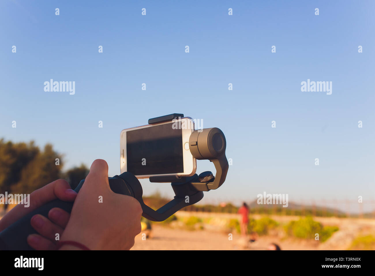 I germogli di persona al telefono con un manuale elettronico stabilizzatore. Close-up. Vista frontale. Foto Stock
