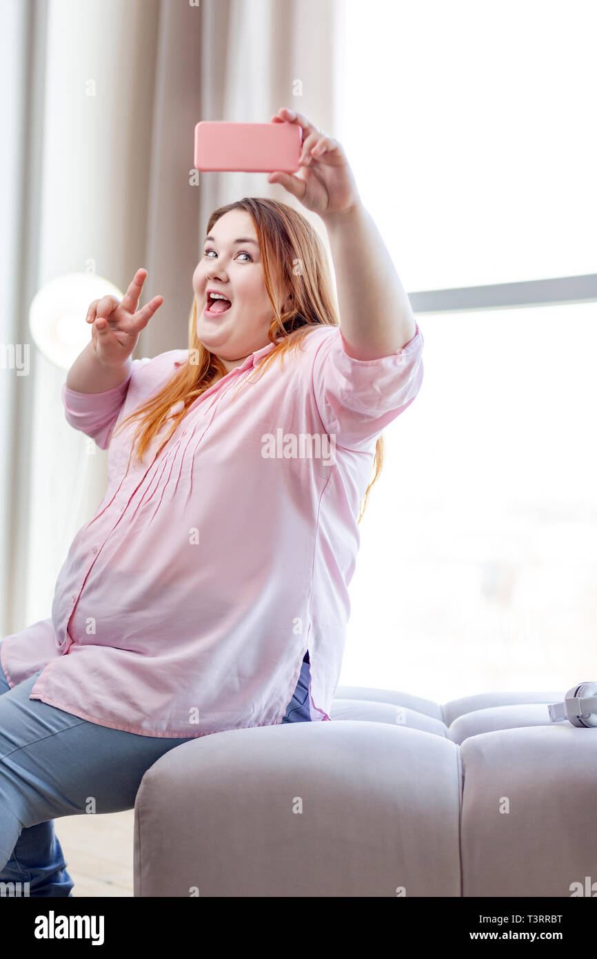 Felice bella donna che mostra un segno di vittoria Foto Stock