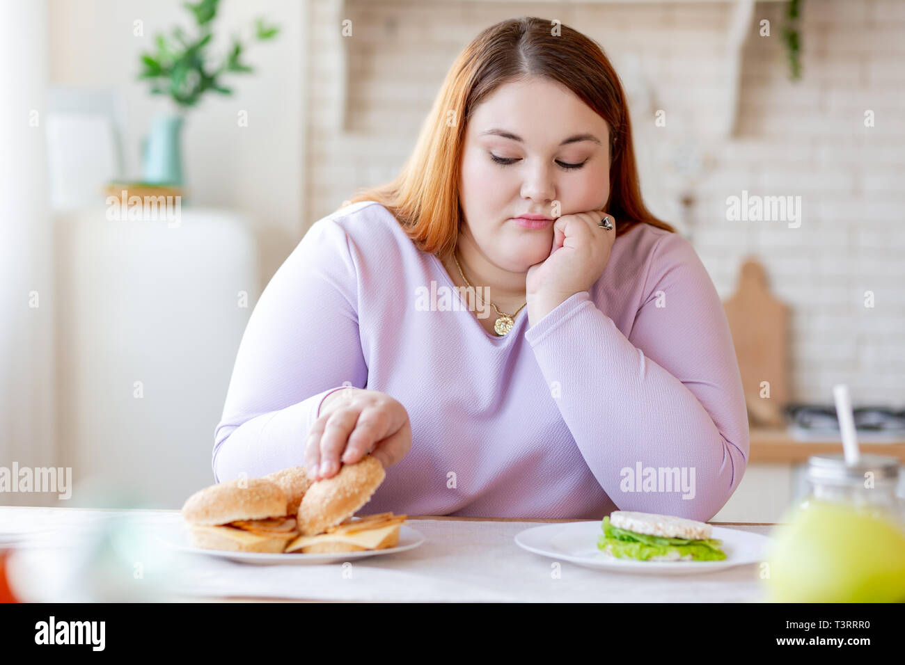 Cupa plump donna pensando al burger Foto Stock