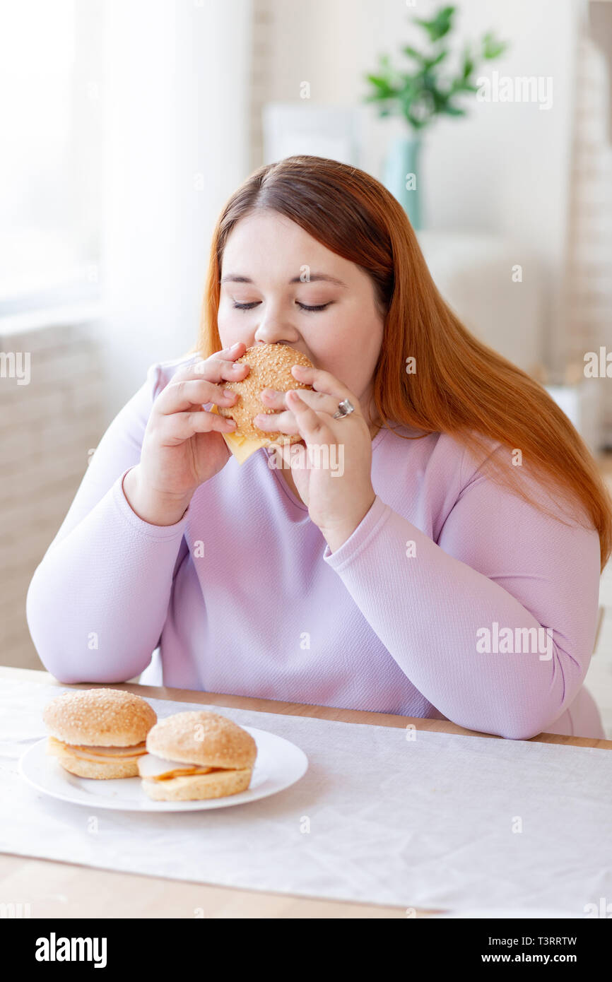 Bella donna grassoccio mangiare una gustosa burger Foto Stock